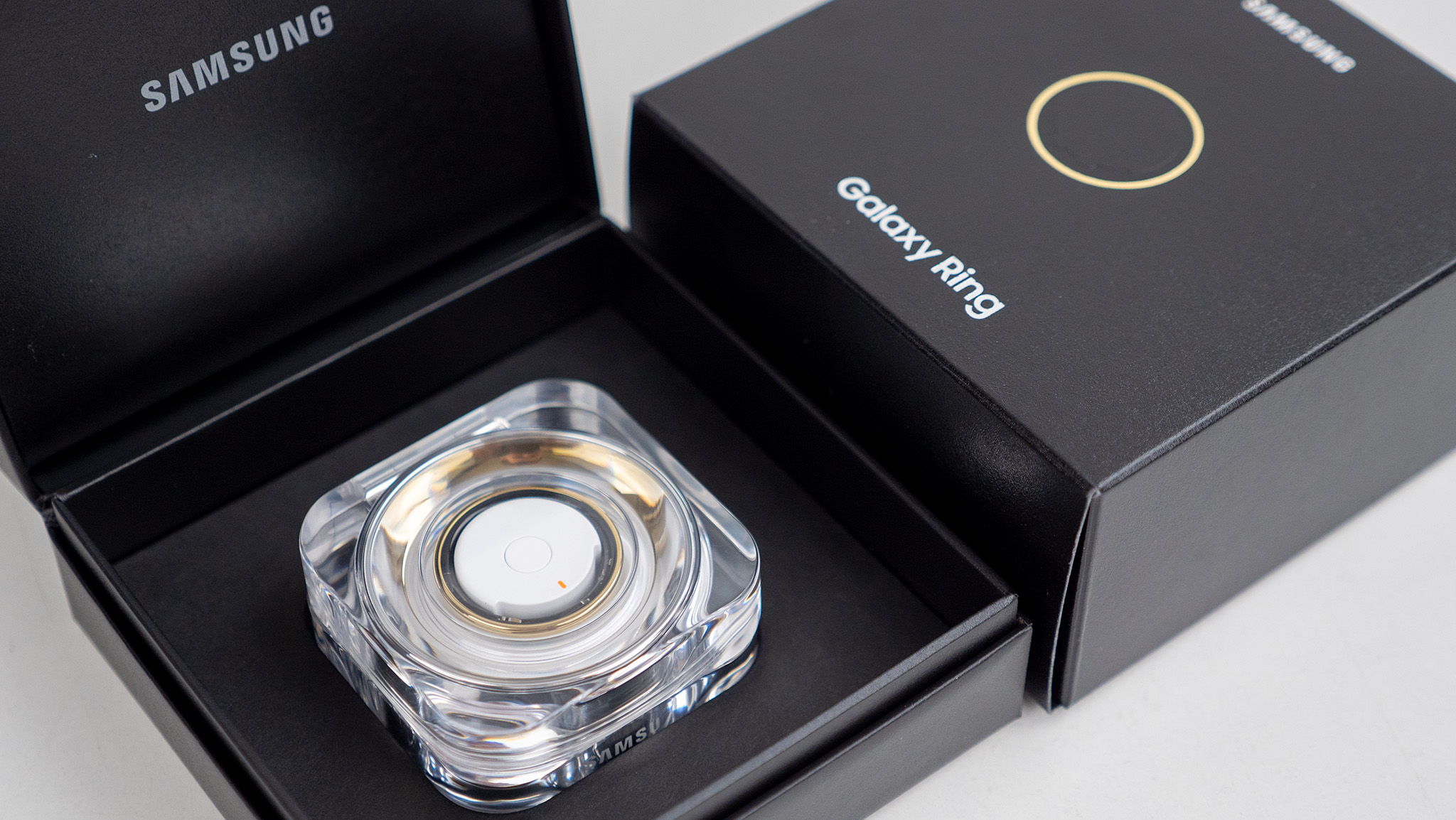 The gold Samsung Galaxy Ring with its box and charging case