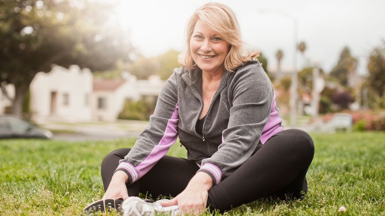 Women smiles as she stretches outdoors on grass