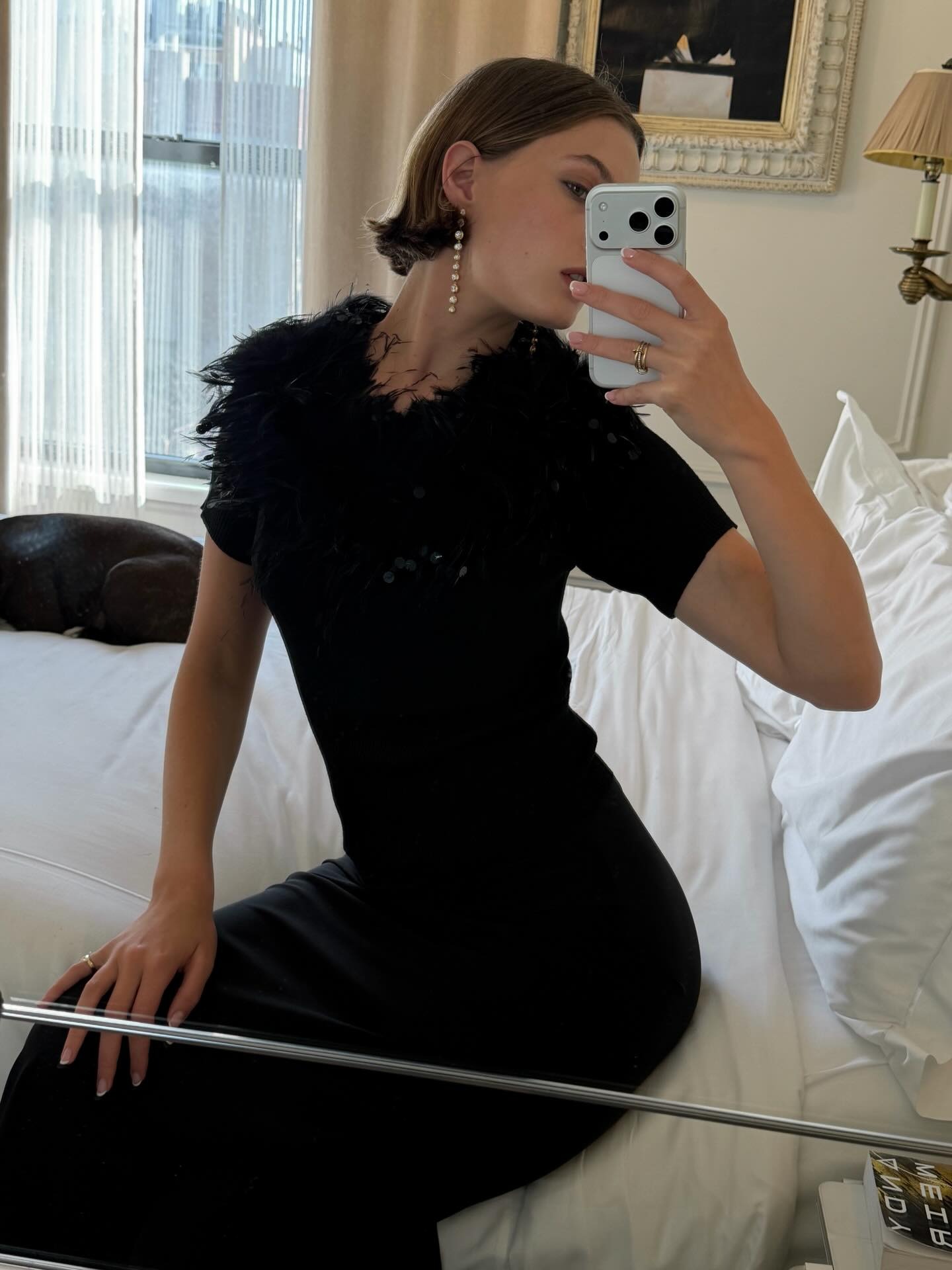 Christie Tyler in New York wearing dangly minimalist earrings with a vintage YSL feathered top.