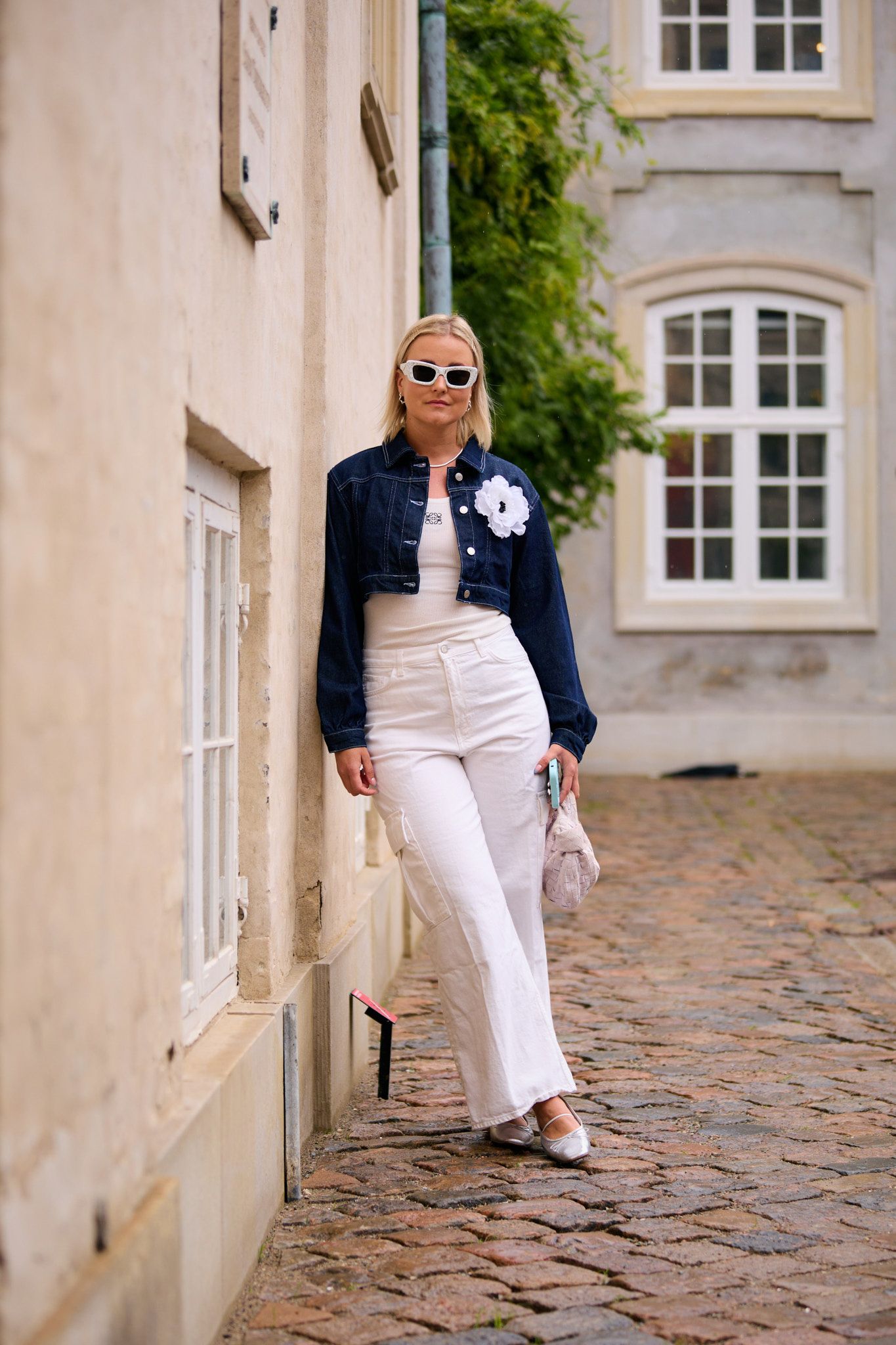 a woman wears high-waisted jeans with a white tee, jacket, and heels.