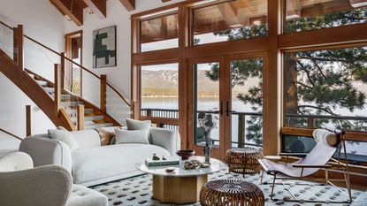 living room with vaulted roof staircase and view of lake with patterned rug and white sofas