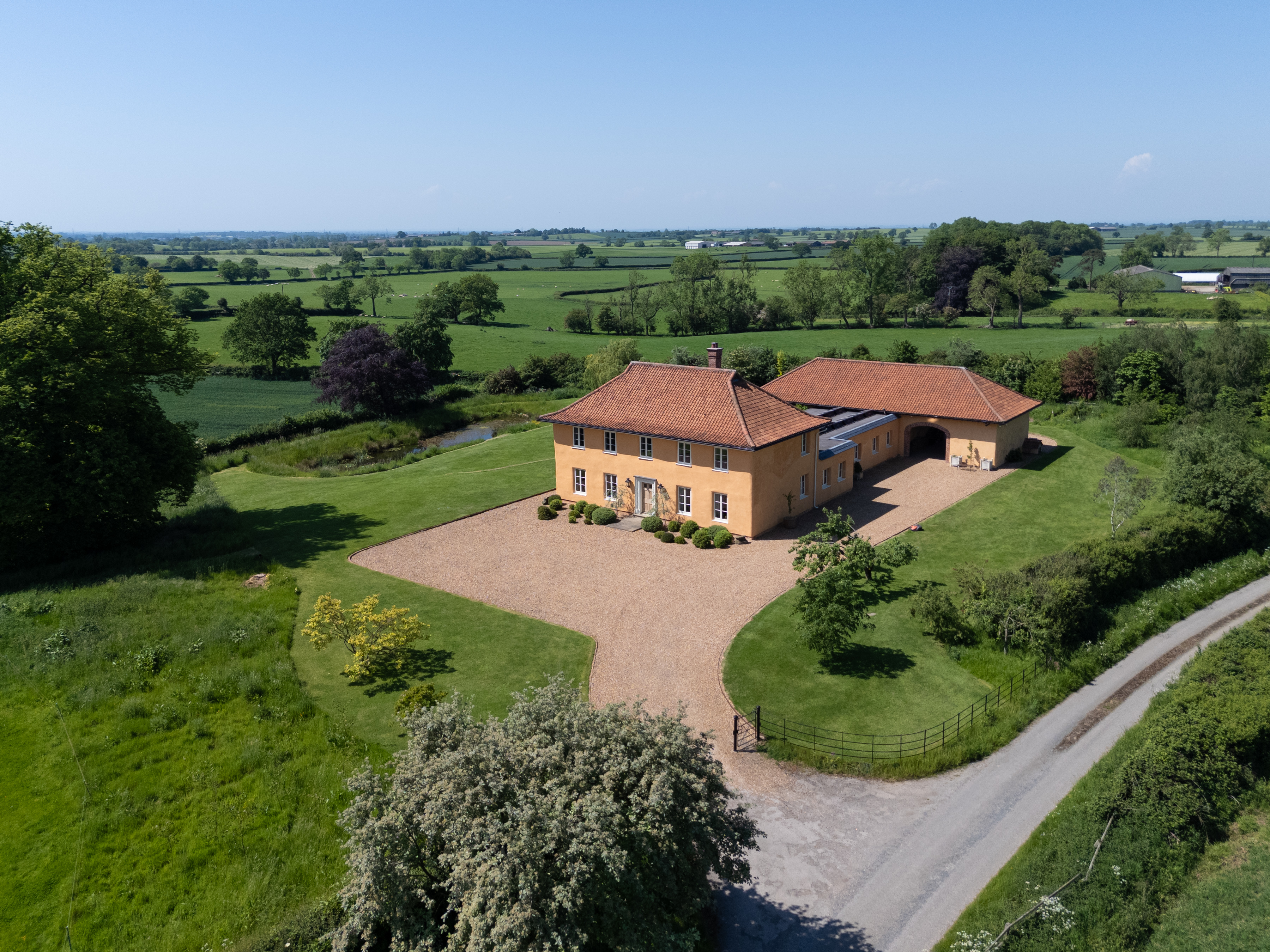 Details of the Lime House in Yorkshire. It is yellow, with a red tiled roof surrounded by green fields. Inside, wood panelled walls contrast with stone fittings and floors for a very farmhouse feel.