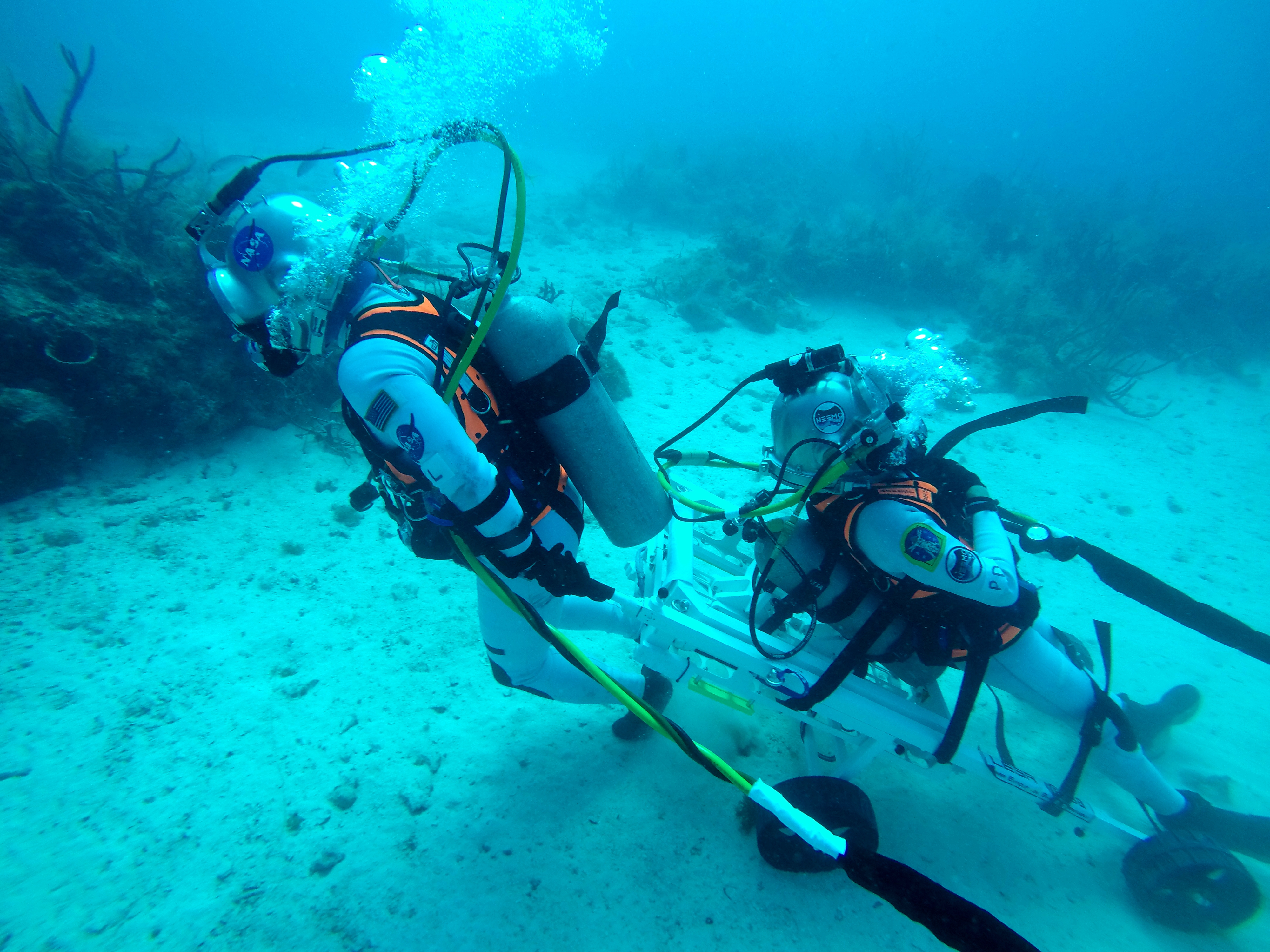 NASA astronaut Kjell Lindgren pulled ESA astronaut Pedro Duque during a simulated moonwalk beneath the Atlantic Ocean. The pair tested a new instrument that allows for the safe and rapid transfer of a fallen companion despite the bulkiness of spacesuits. 