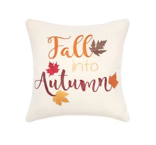 A white pillow with red and yellow writing and autumn leaves