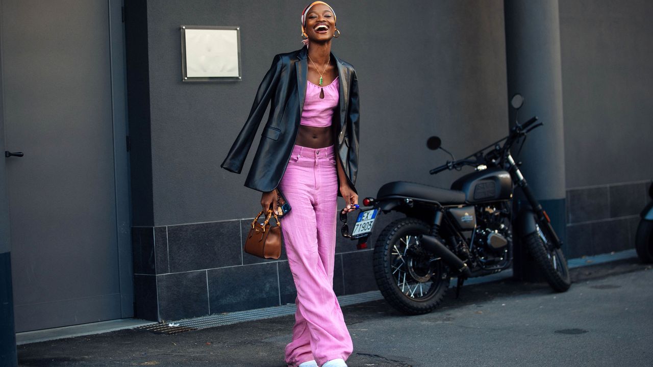 Model Mayowa Nicholas wears a pink matching set, headscarf, black leather jacket, small Gucci brown leather bag, and white sneakers after the Missoni show during the Milan Fashion Week