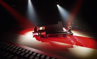 Large piano on stage with red lights