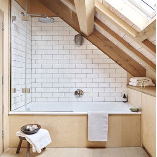bathroom with wooden stool, white bath with wooden panelling and wooden ceiling beams