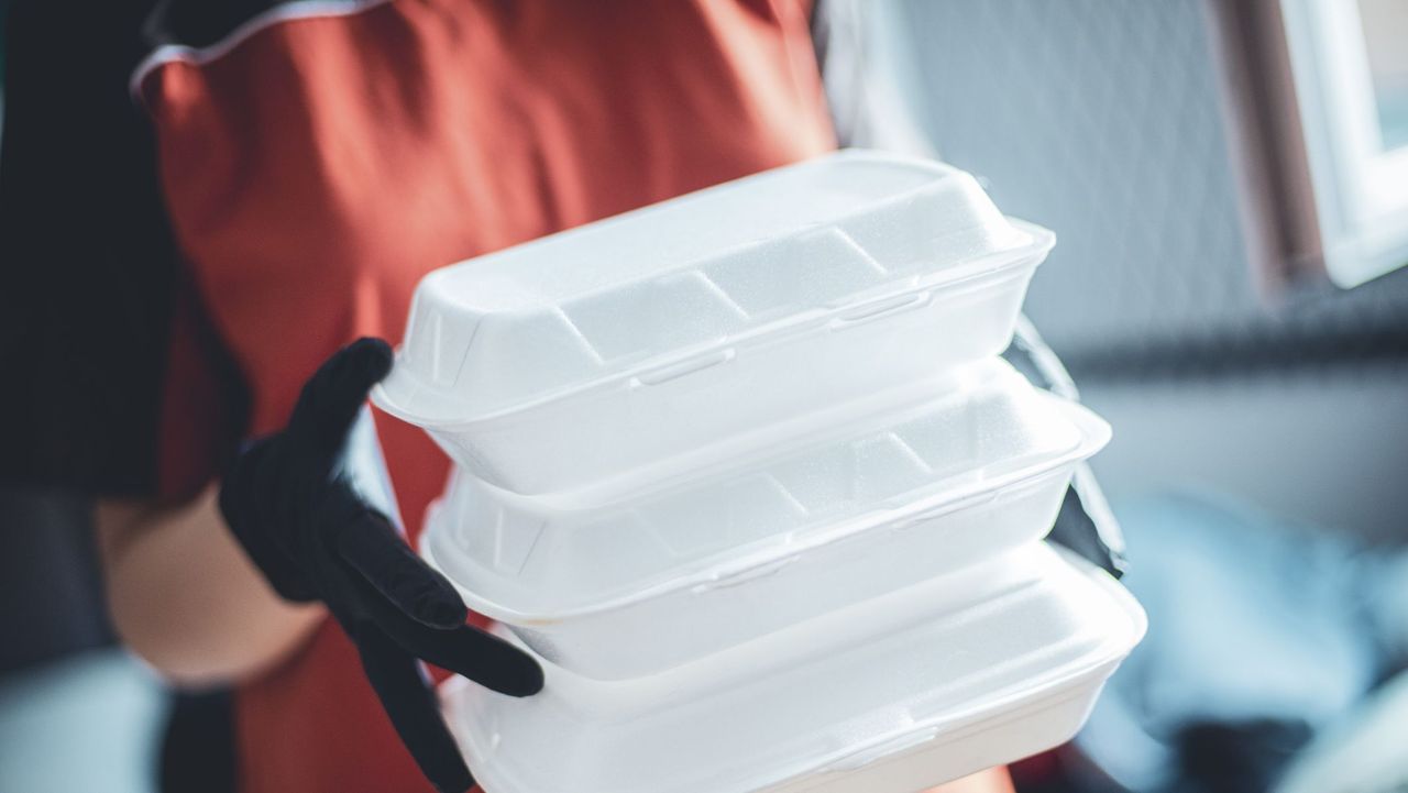 delivery woman with protective medical mask and gloves holding food box