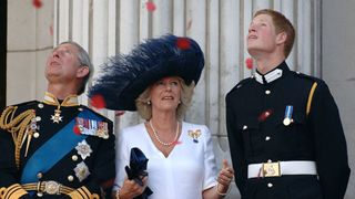 The Prince of Wales, the Duchess of Cornwall and Prince Harry watch the flypast over The Mall of British and U.S. World War II aircraft from the Buckingham Palace balcony on National Commemoration Day July 10, 2005 in London.