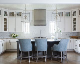 U-shaped kitchen with upholstered bar chairs and duo of caged pendant lights hanging above