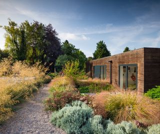 A contemporary home with a gravel pathway and prairie style planting