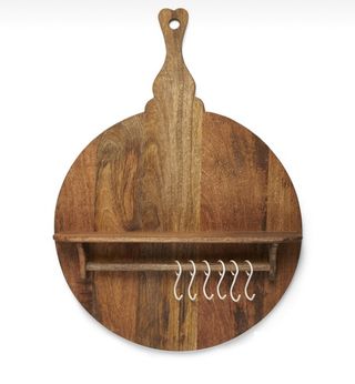A round wooden back board with a small shelf and horizontal dowel rod and metallic hooks.