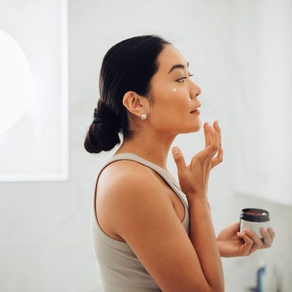 Woman applying cream to her face