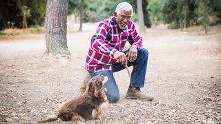 Man playing fetch with dog in forest