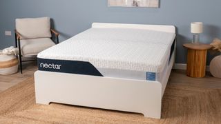 The image shows the Nectar Classic Memory Foam mattress on a white bed frame in a pale blue bedroom