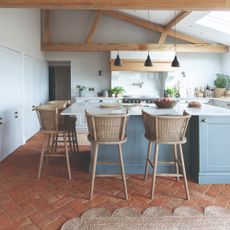 An open-plan kitchen with a high ceiling and three pendant lights hung above the kitchen island