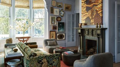 living room with gray blue walls and gallery wall round bay window and black fireplace with patterned sofa