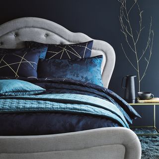 bedroom with navy blue wall and navy cautions on grey bed