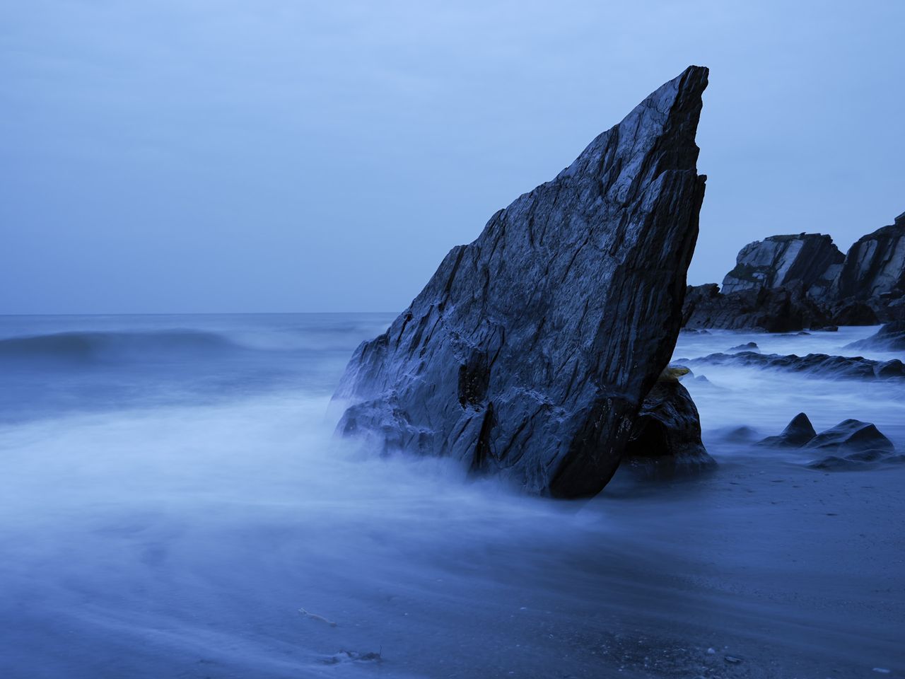 OM System OM-3 sample photos: jagged rock in the ocean, with the water movement blurred