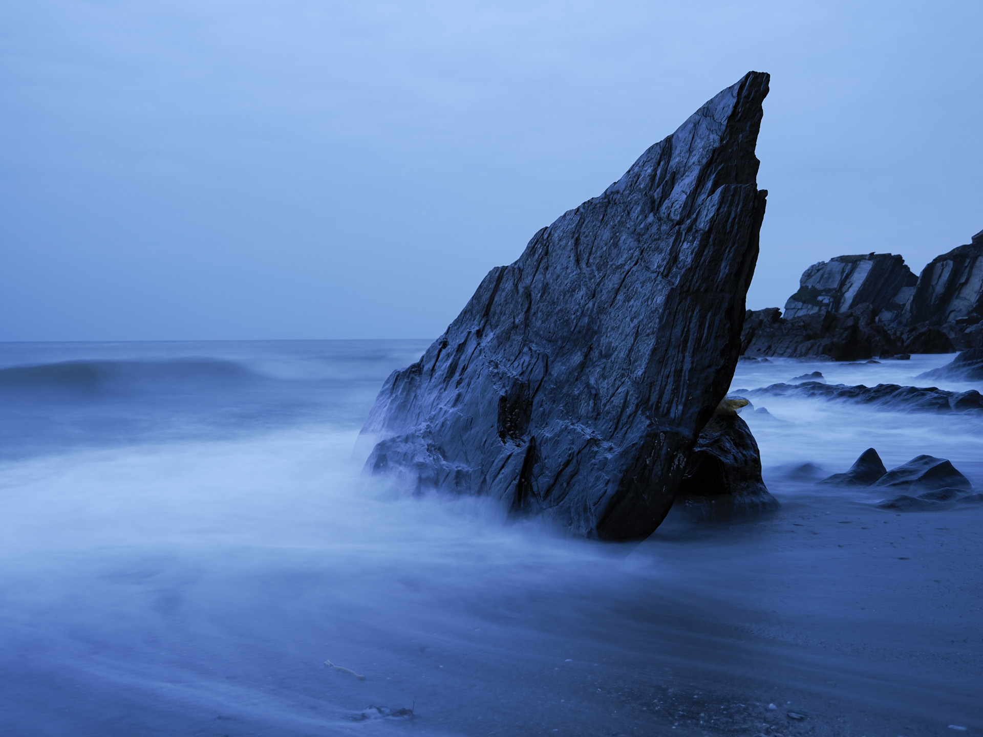 OM System OM-3 sample photos:  jagged rock in the ocean, with the water movement blurred