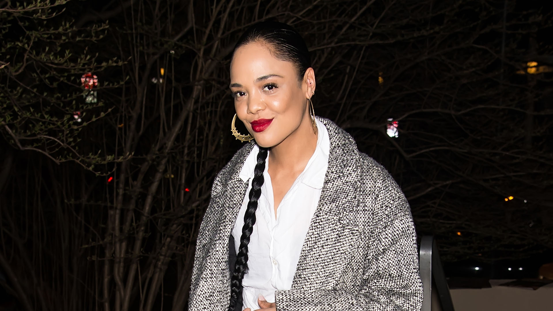 Tessa Thompson wearing a plaid coat, white shirt, and black pants