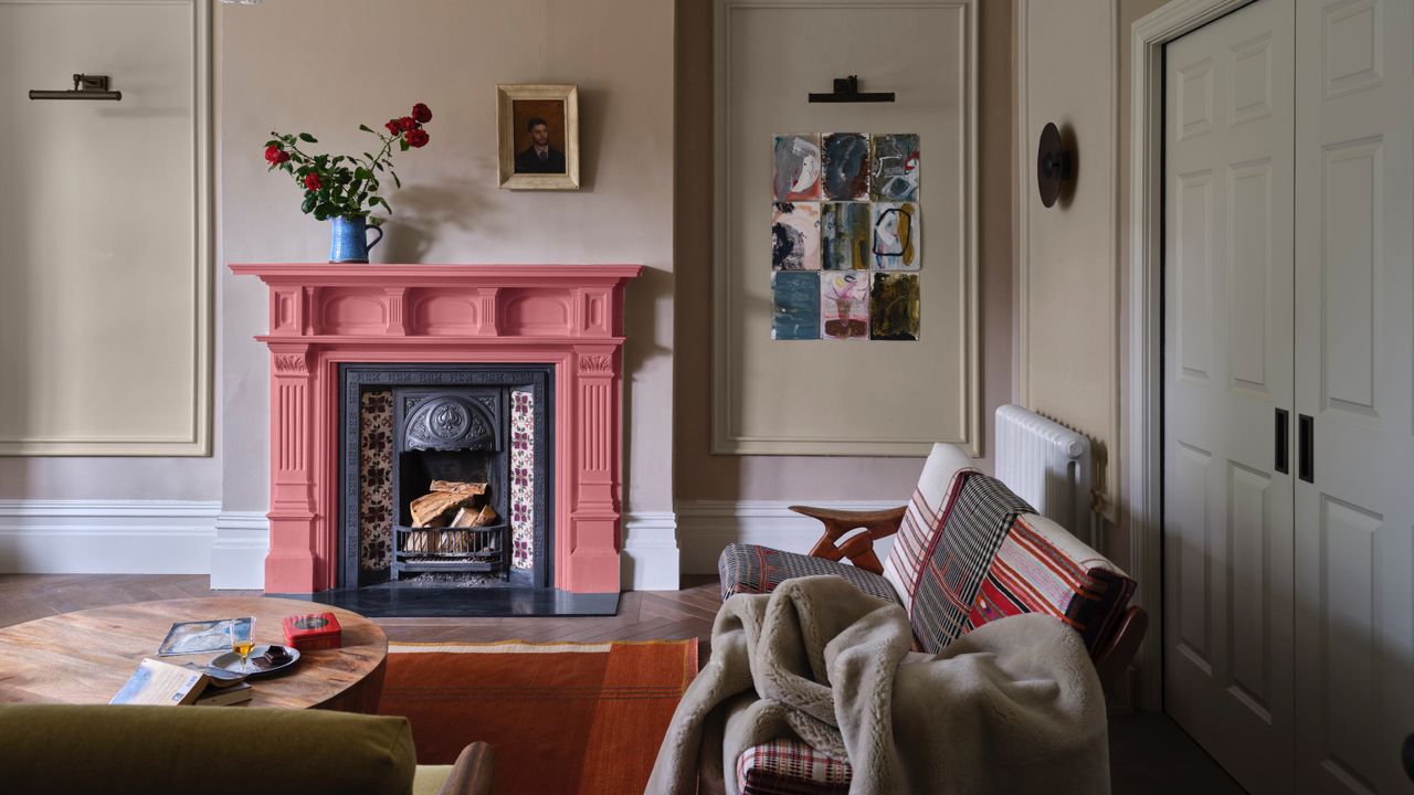 neutral living room with coral painted fireplace, striped couch, artwork, paneling, rug, coffee table, blankets, Farrow &amp; Ball 