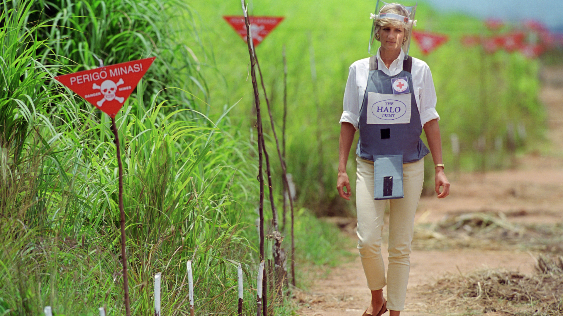 Princess Diana wearing protective gear walking through a mine field in Angola