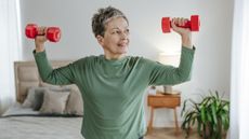 Woman exercising with dumbbells in domestic setting
