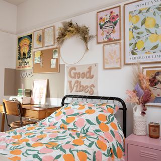 White child's bedroom with fruit bedding, gallery wall, dried flowers, Frida Khalo artwork, black metal bed frame