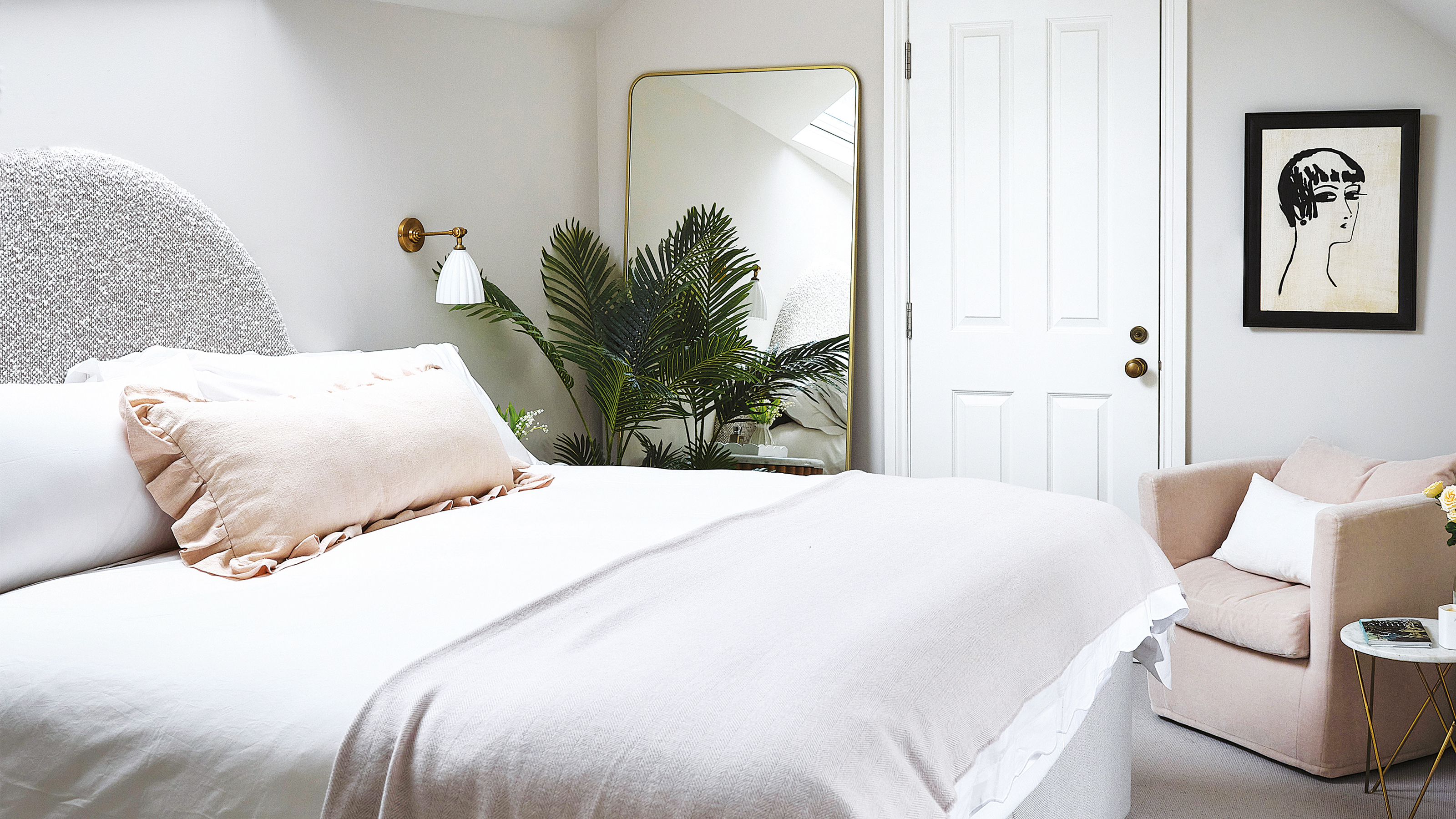 A white loft bedroom with a large mirror leaning against the wall and a plant