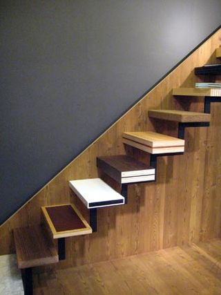 Wooden staircase with plain black walls and no banisters