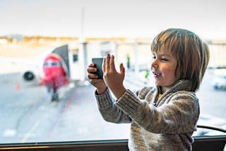Hvilket mobilabonnement er best for barn og unge?: Gutt som tar selfie på en norsk flyplass.
