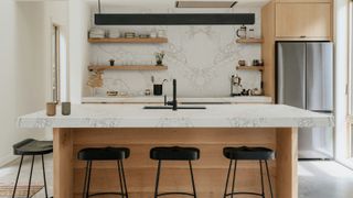 modern light wood kitchen with large bookmatched white and pale grey quartz splashback