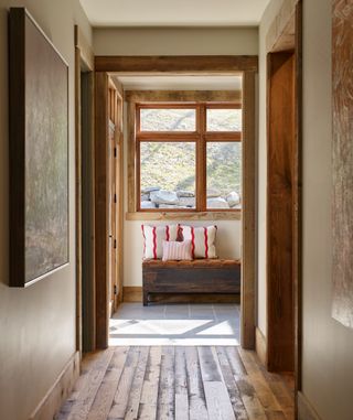 farmhouse hallway with cushions on a bench, wooden flooring, doorframes, window