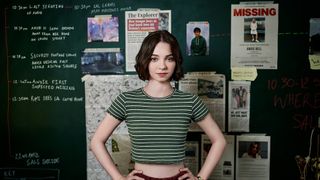 A Good Girl's Guide to Murder star Emma Myers in front of a board of clues