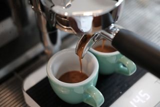 Espresso being poured into two espresso cups