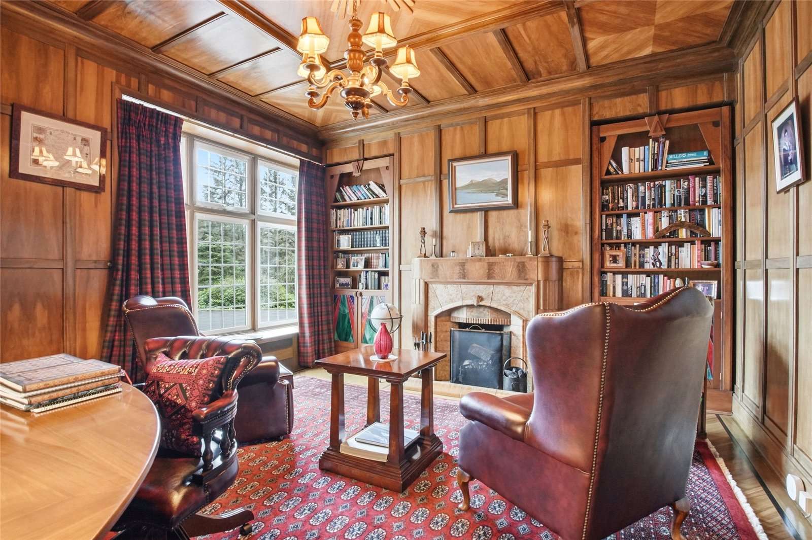 A wood-panelled study with two armchairs in front of a fireplace