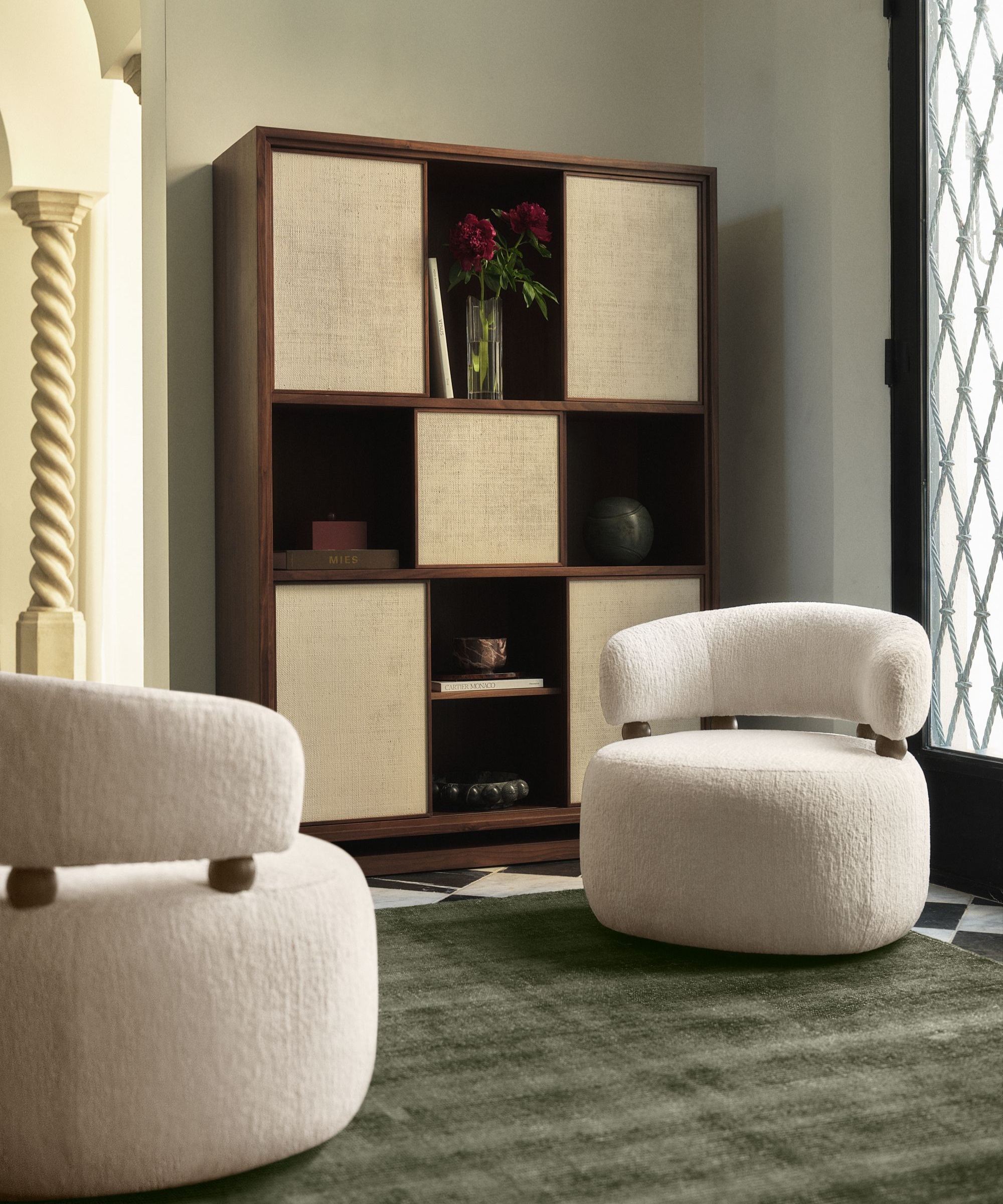 a sitting area with two chairs and a cabinet with fabric panels