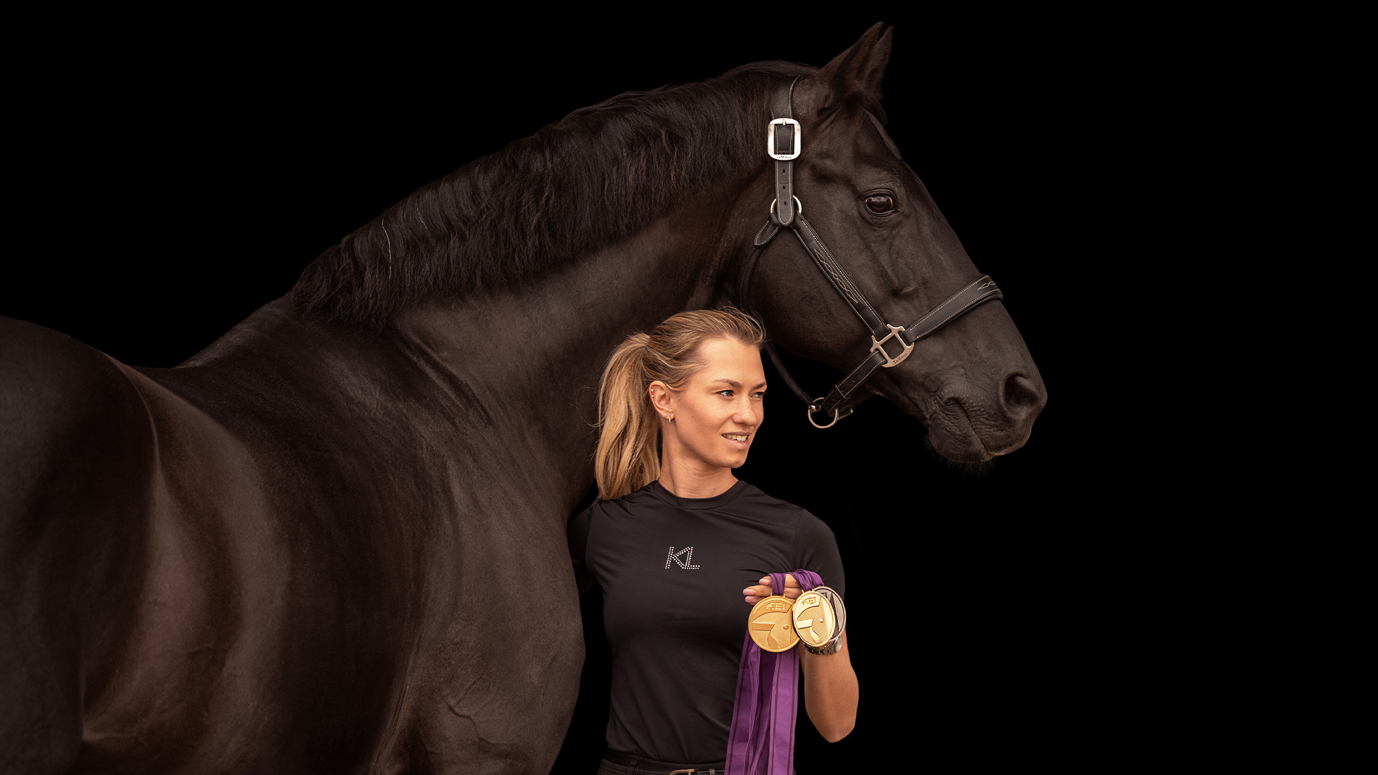 Lottie Fry stood at Glamourdale&rsquo;s shoulder holding medals, with a blacked out background