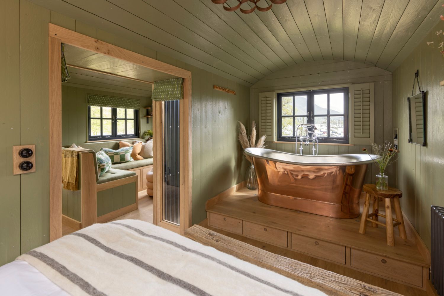 Image of a bedroom in Another Place, showing brass bath under the window and bright green walls