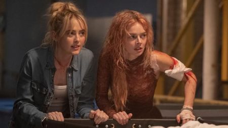 Kathryn Newton and Samara Weaving push a laundry cart while injured