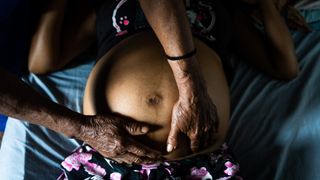 Midwife rubs belly of pregnant woman.