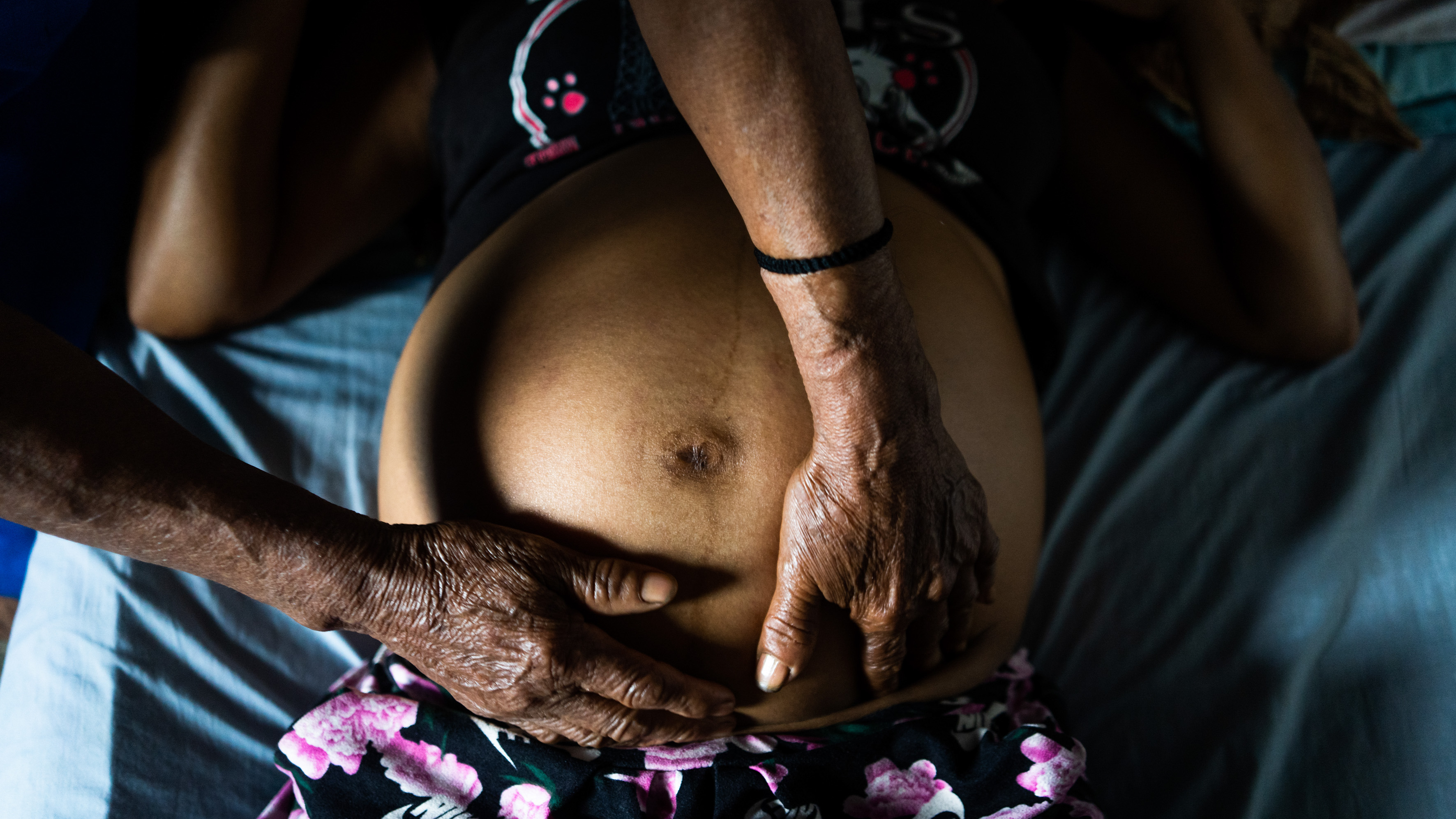 Midwife rubs belly of pregnant woman.