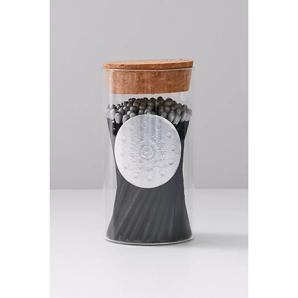 a glass jar of black matches with silver tips