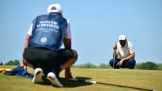 Scottie Scheffler lines up a putt with his caddie