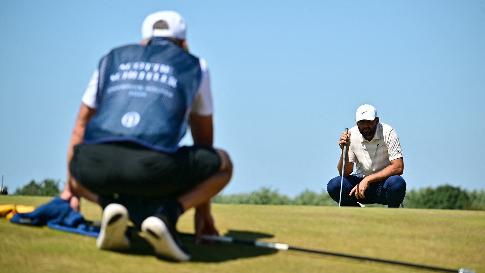 Scottie Scheffler lines up a putt with his caddie
