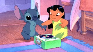 Still from the animated movie Lilo & Stitch (2002). A young Hawaiian girl is holding the hand of a blue, koala-like alien, hovering it's claw over a record player.