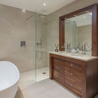 bathroom with drawers and glass wall with showering area and mirror on wall