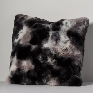 Luxurious faux fur pillow on gray background.