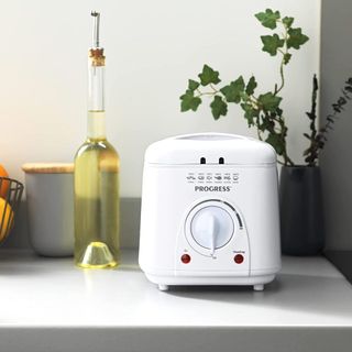 Progress deep fat fryer on white counter next to a bottle of cooking oil